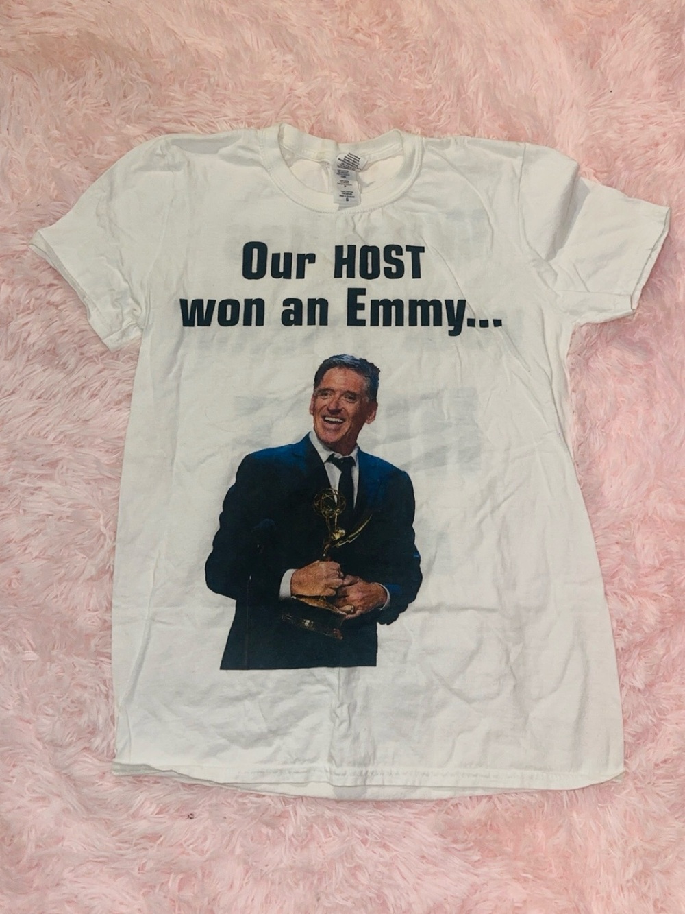 White t-shirt of a man holding an Emmy award with the text our host won an emmy.